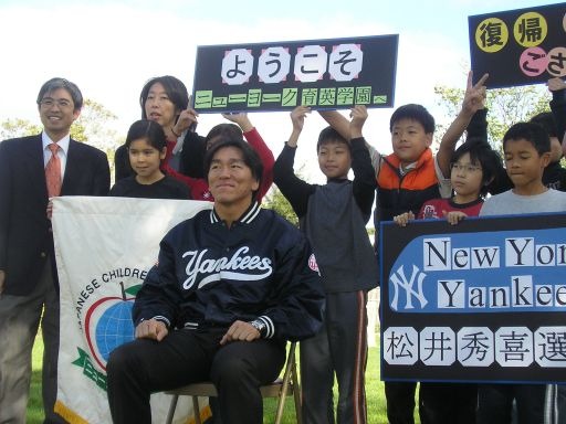 「ようこそ」「New York Yankees 松井秀喜選手」のボードを掲げた子どもたちと