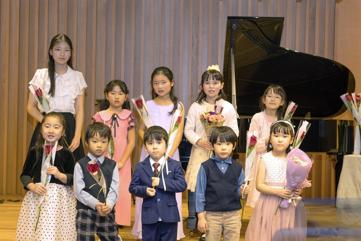 Performers lined up on stage holding bouquets