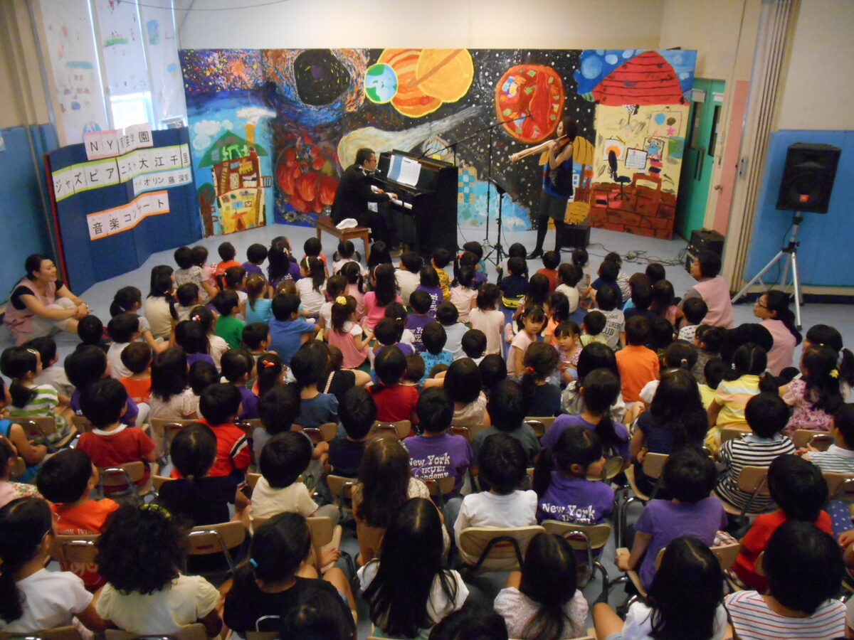 うしろから見た会場。床いっぱいに子どもたちが座っている