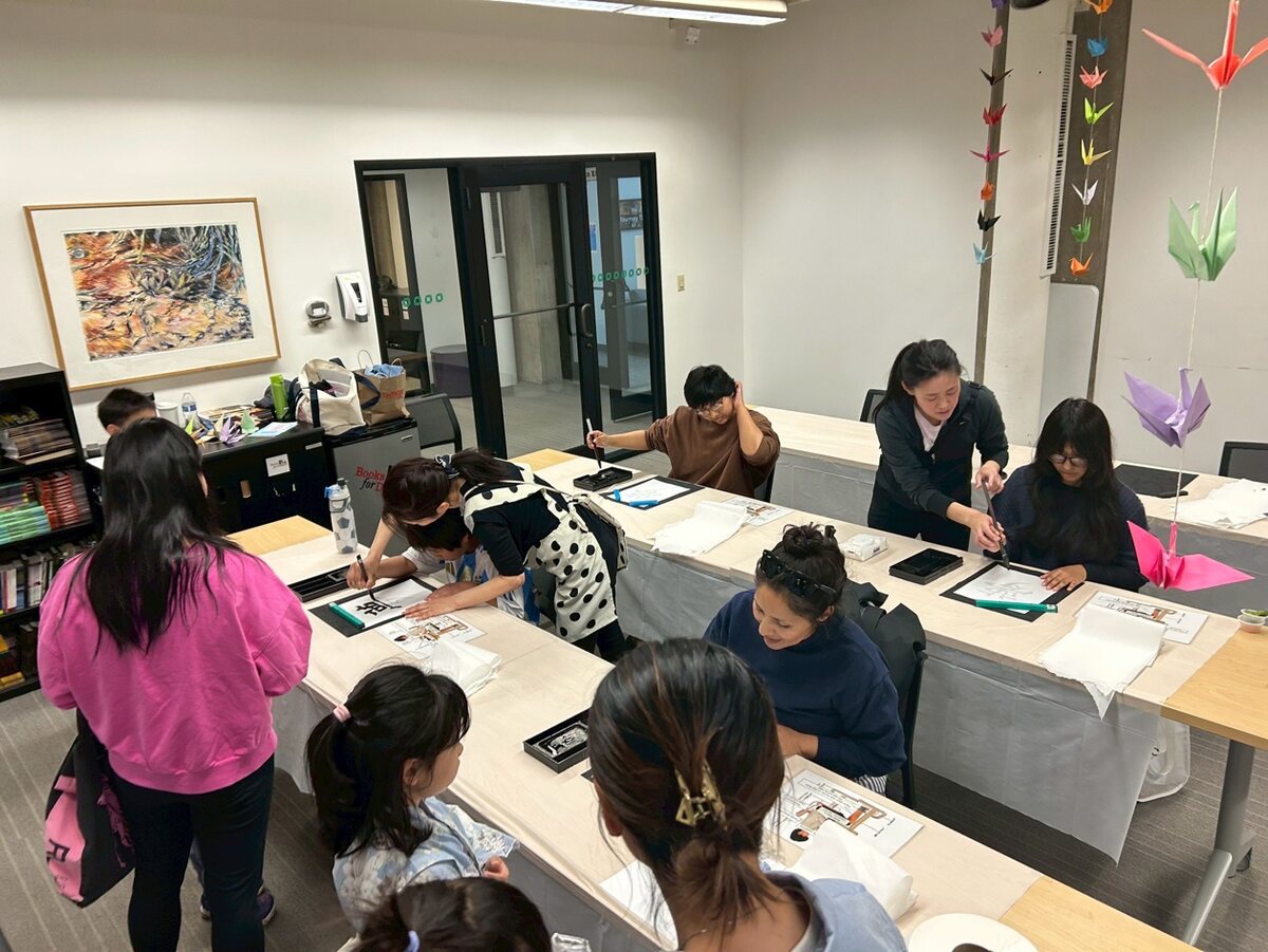 書道体験のコーナーで筆をとる来場者