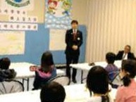 教室の前に立つ男性と、席に着いた子どもたち