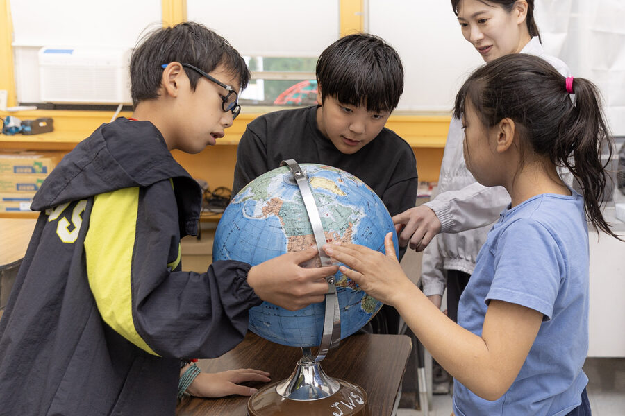 地球儀を囲んで学ぶ児童と先生